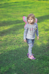 Pretty toddler girl with butterfly wings, playing in the park