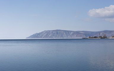 Baikal lake spring landscape view. Snow-covered shore of the lake. Rocky forested coastline.