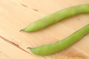 Pods of fava on wooden background