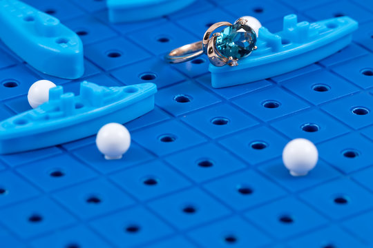 gold ring lies on the game Board with toy military ships