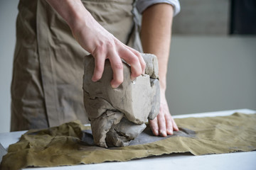 Obraz na płótnie Canvas Man crumples piece of white clay for sculpting