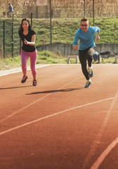 Fototapeta premium Young couple exercise on athletics track