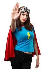 Pretty superhero girl making stop sign