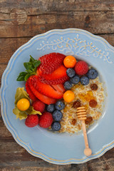 Fiocchi d'avena con latte, miele di castagno, uvetta, fragole, lamponi, mirtilli, physalis