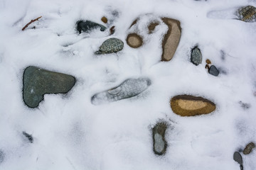 Closeup stones and human footprint with snow and ice in nature pattern