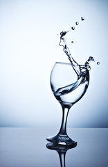 Water splashing out of a tall wine glass.