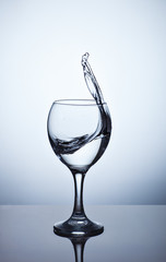 Water splashing out of a tall wine glass.