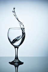 Water splashing out of a tall wine glass.