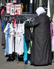Fototapeta premium Frau mit Kopftuch und langem Mantel an einem Kleiderständer in Berlin-Kreuzberg
