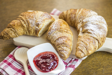 Croissants breakfast composition on kitchen table.
