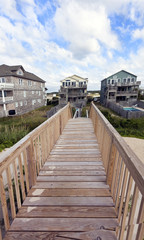 Fototapeta na wymiar Wooden walkway leading to upscale vacation beach rentals.
