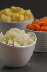 chopped vegetable in white bowls on wood