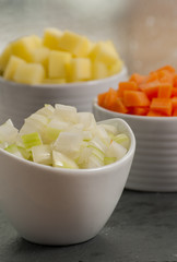 chopped vegetable in white bowls on wood