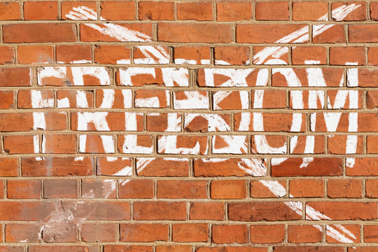 Brick wall with the crossed out word FREEDOM