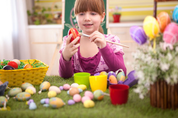 Fototapeta na wymiar happy smiling young girl painting eggs in home kitchen