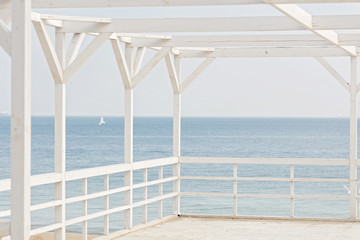 Fototapeta na wymiar White wooden gazebo on a sea background. Selective focus.