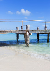 Obraz premium Bridge over turquoise water. The Caribbean sea shore with white sand and a wooden pier.