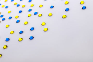 Precious sparkling rhinestones blue and yellow colors on a white acril background.