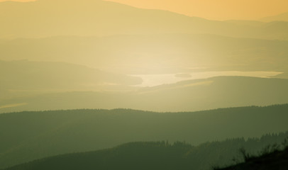 A beautiful, colorful, abstract mountain landscape with a hot summer haze in warm green tonality. Decorative, artistic look.