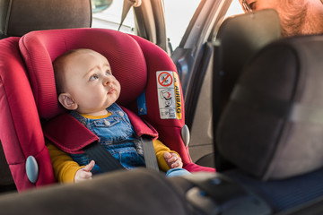 Father fasten his baby in car seat