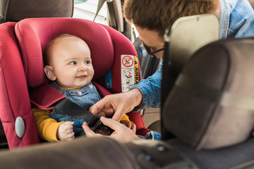 Father fasten his baby in car seat