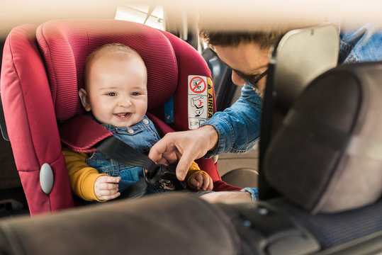 Father fasten his baby in car seat