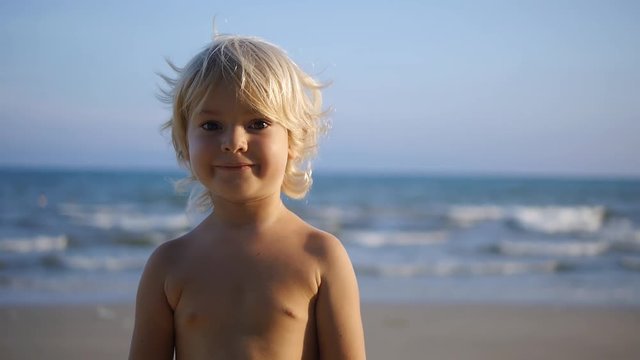 A happy child laughing, waving hands in sea background slow motion x2