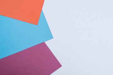 Color papers geometry flat composition background with violet, blue, orange, grey tones.