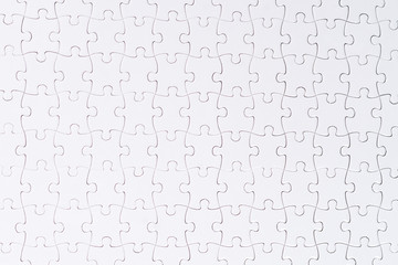 Incomplete white puzzles on wooden table.