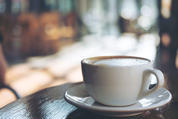 A cup of hot latte coffee on vintage wooden table in cafe