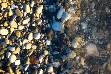 sea pebble beach with multicoloured stones, waves with foam