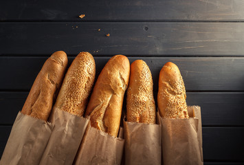 French baguettes with sesame seed on black wooden background