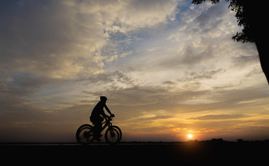 Fototapeta premium Silhouette of a woman and man biker in the sunset