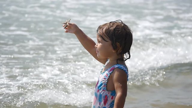 Young man taking photo of cute little child showing sea star on the beach. Family enjoying in vacation on coastline.  Slow motion 50Fps. 