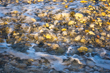 sea pebble beach with multicoloured stones, waves with foam