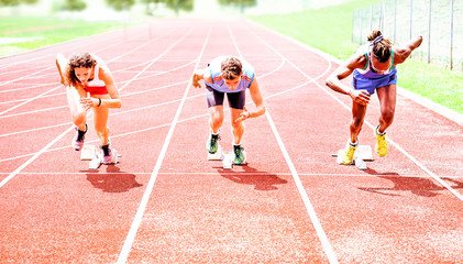 Row of multiracial runners at start grid on red athletics track - Professional sprinters explosive speed training - Concept of preparation for sports events and competition 
