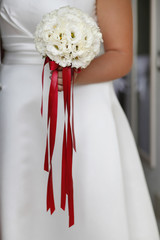 Mazzolino di fiori bianchi con lacci rossi tenuto da una sposa