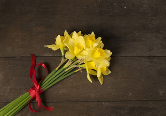 Bunch of yellow daffodils with blossom on the wooden background.