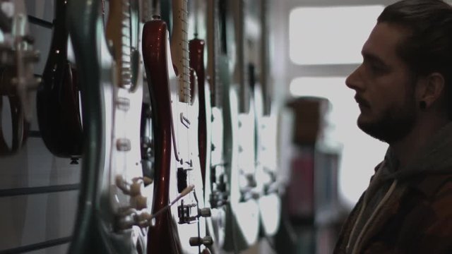 Young adult male looking at guitar in shop