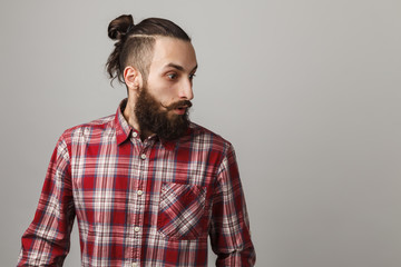 Bearded handsome man surprised in red squared shirt on grey background