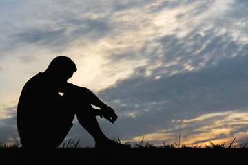 Silhouette of a man sitdown with so sad in the sunset.