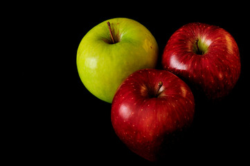 Two red apples and one green on a dark background