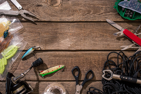 Fishing tackle - fishing spinning, fishing line, hooks and lures on wooden background.