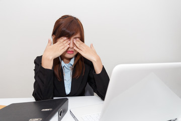 Businesswoman with eyes pain at office desk - business concept.