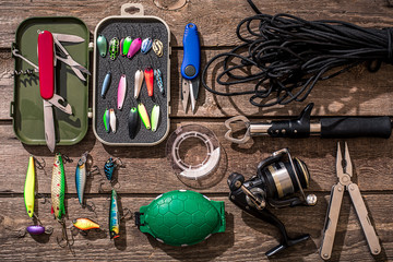 Fishing tackle - fishing spinning, fishing line, hooks and lures on wooden background.