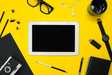 Flat lay display of business office gadgets with notepad, vintage camera, pen, develop, glasses and etc. Top view. Black office objects on a yellow background