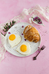 Fried egg in form heart on a pink background