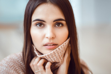 Obraz premium Closeup portrait of pensive white Caucasian European brunette young beautiful woman model with long dark red hair and brown eyes in turtleneck sweater, looking in camera