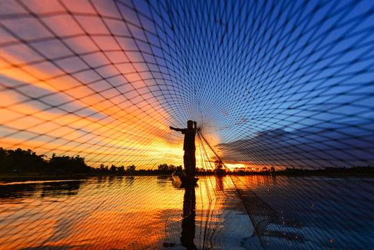 The silluate fisherman trowing the nets  on boat in river  at during sunrise,Thailand