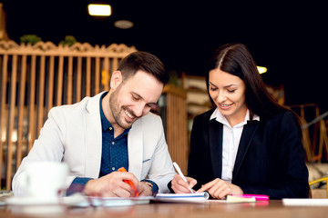 Young man and woman sitting at table and making notes.